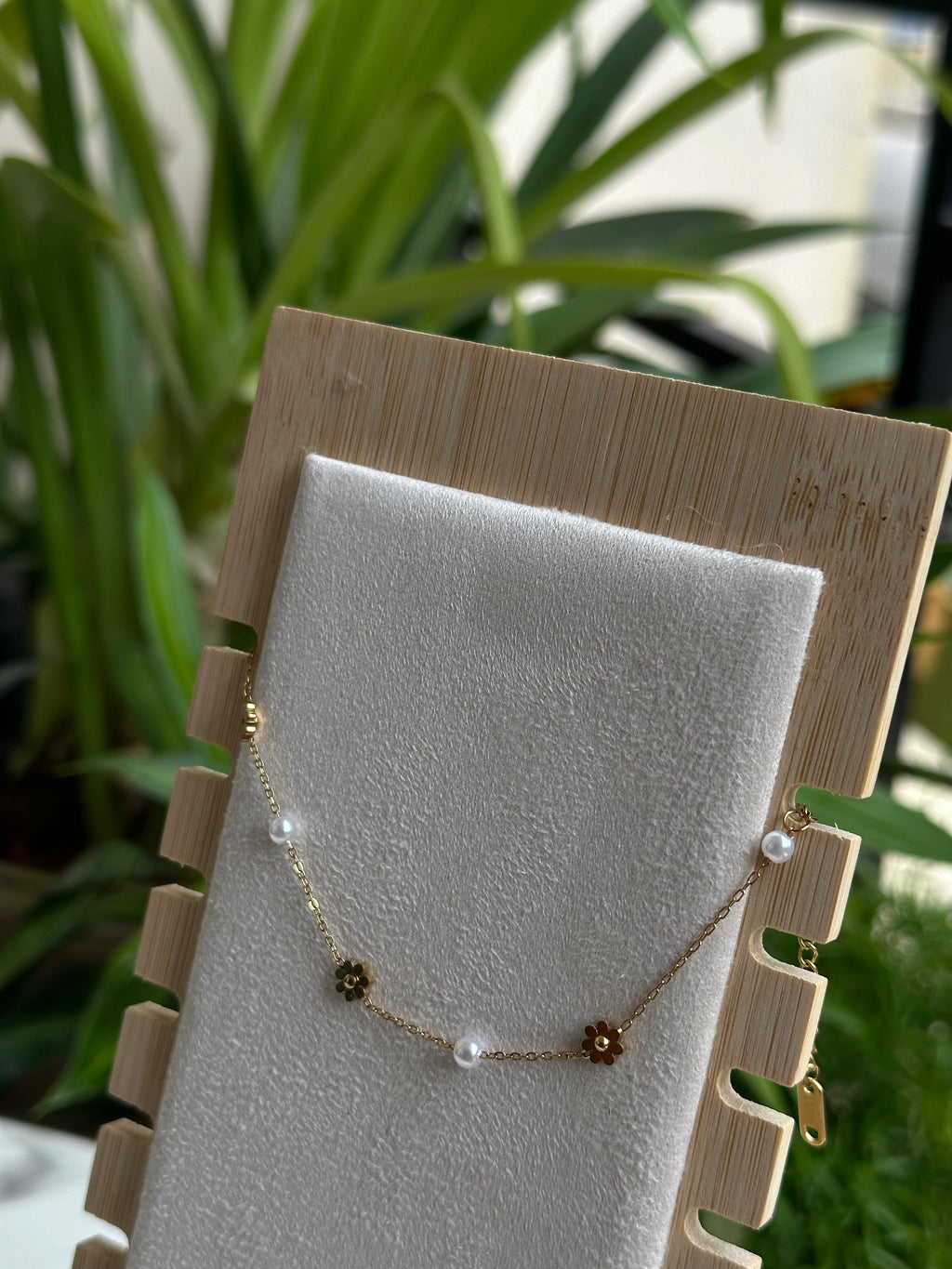 Gold daisy flower and pearl bracelet on white display stand