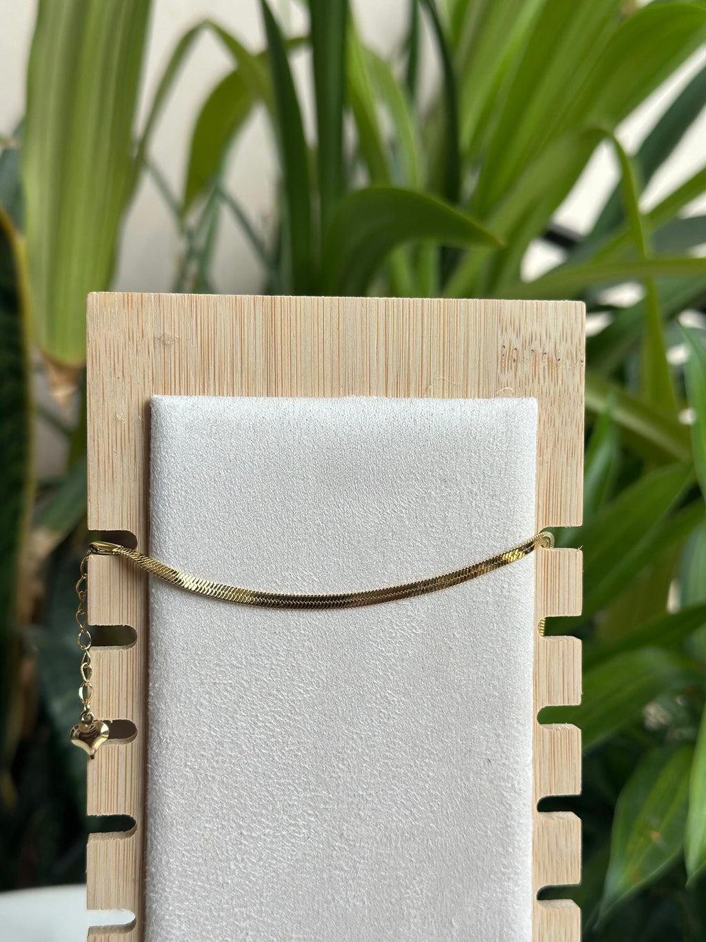 Gold herringbone flat chain bracelet on white display stand