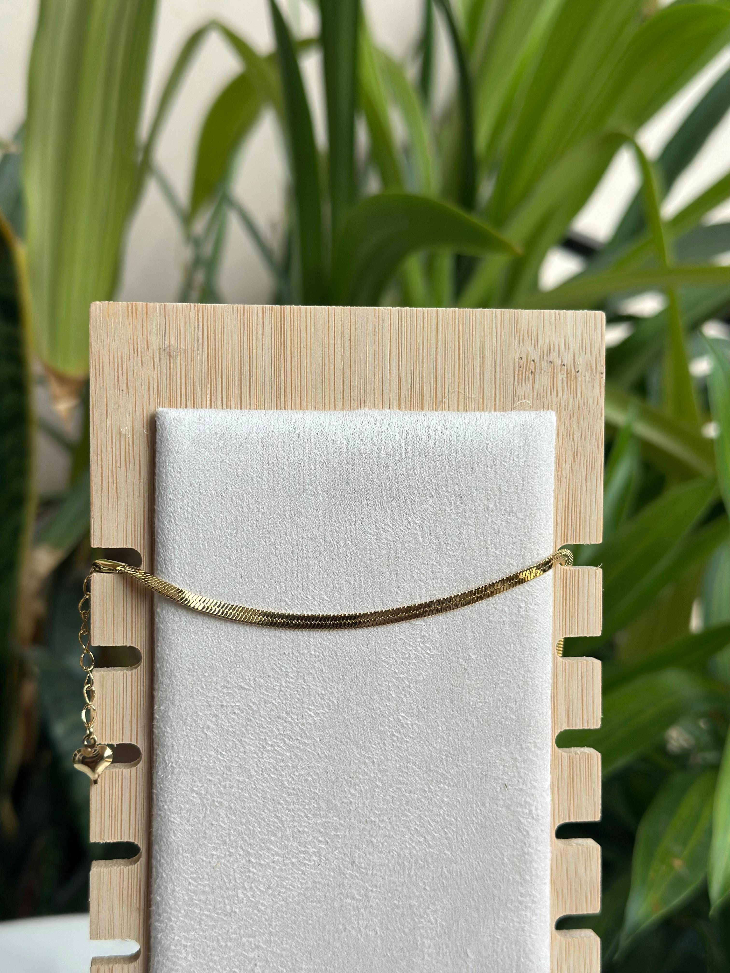 Gold herringbone flat chain bracelet on white display stand