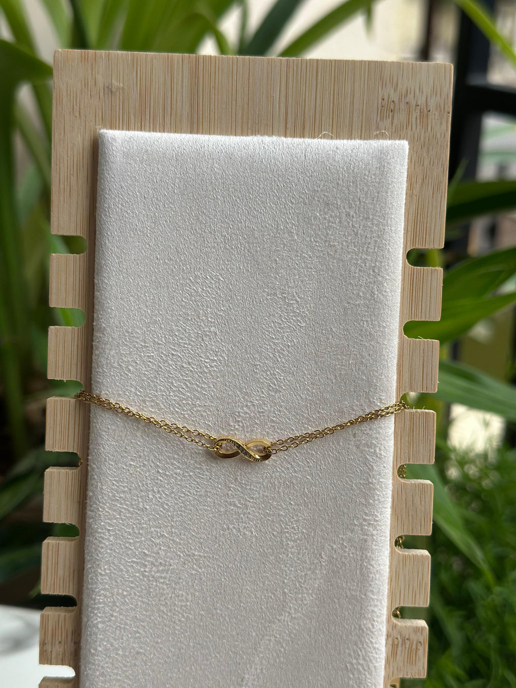 Gold infinity bracelet on white display stand