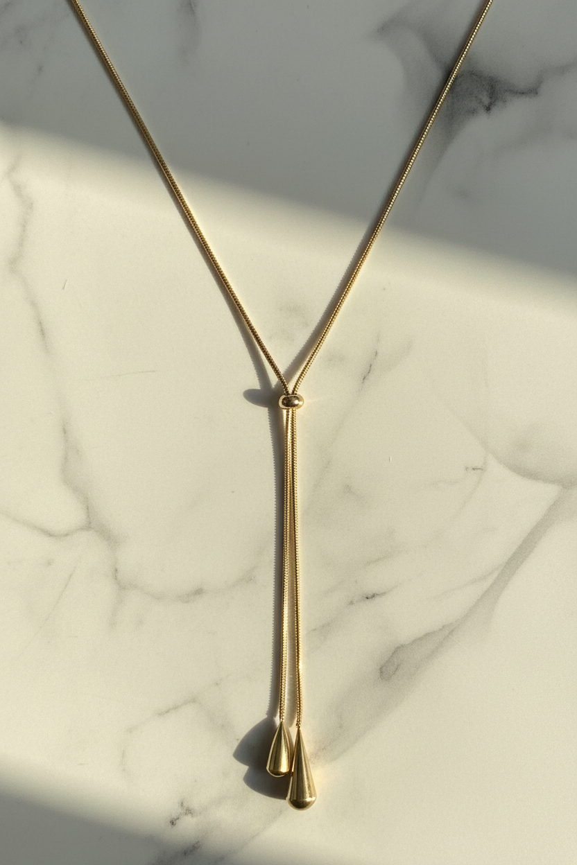 Gold lariat Y-necklace on white marble surface