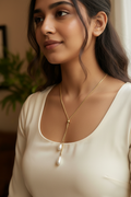 Gold lariat necklace with pearl drops worn by young Indian woman