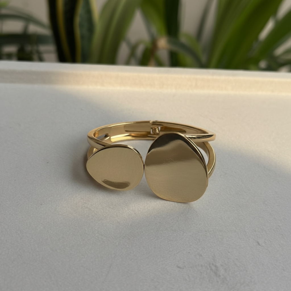 Gold double disc open cuff bangle on white marble surface