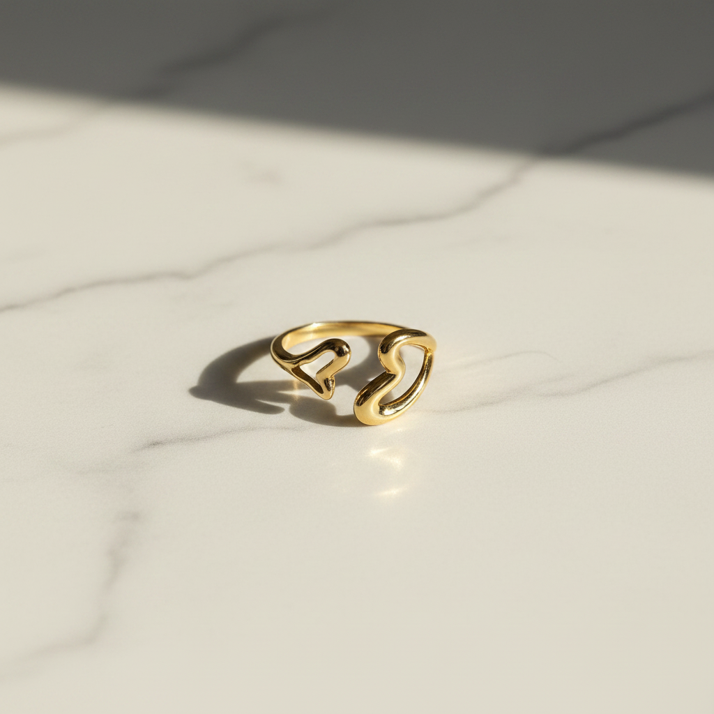 Gold open heart and butterfly ring on white marble surface