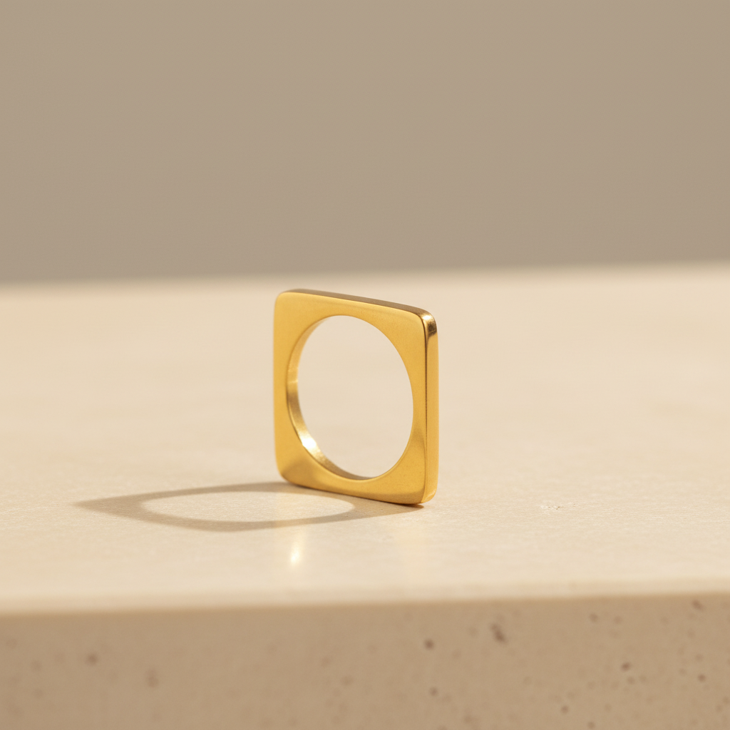 Gold square-loop ring isolated on a warm ivory luxury jewellery studio background