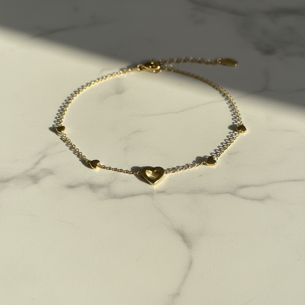 Gold multi-heart charm bracelet on white marble surface