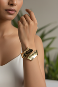Gold wrap bypass cuff bangle worn on Indian woman's wrist